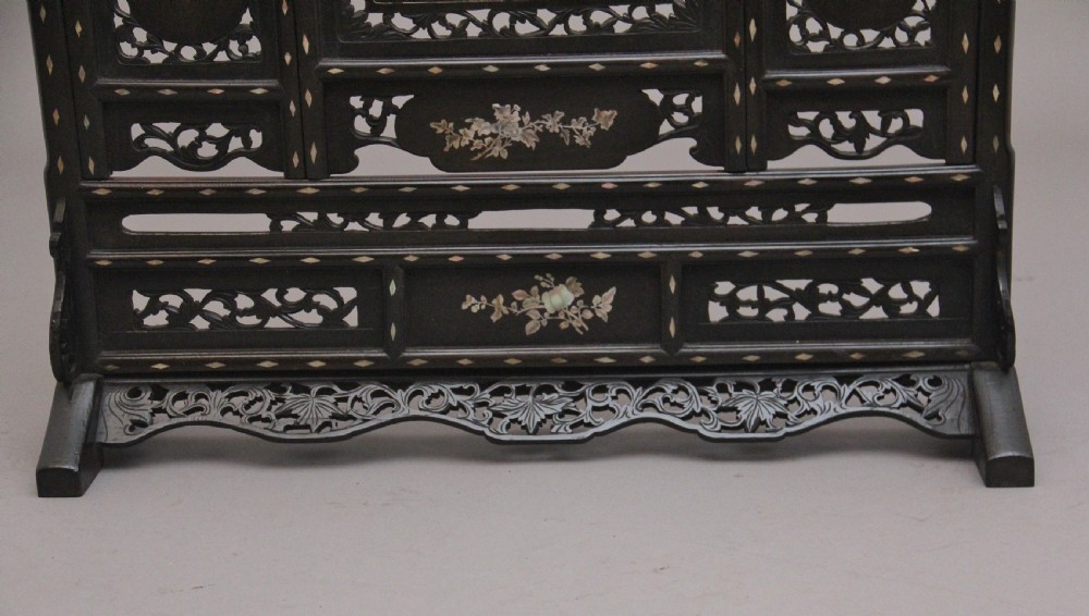 A 19th-century Chinese dark hardwood triptych table screen set with carved openwork borders and detailed mother-of-pearl landscape inlays. View V