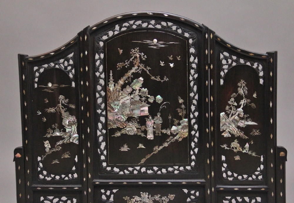 A 19th-century Chinese dark hardwood triptych table screen set with carved openwork borders and detailed mother-of-pearl landscape inlays. View VI