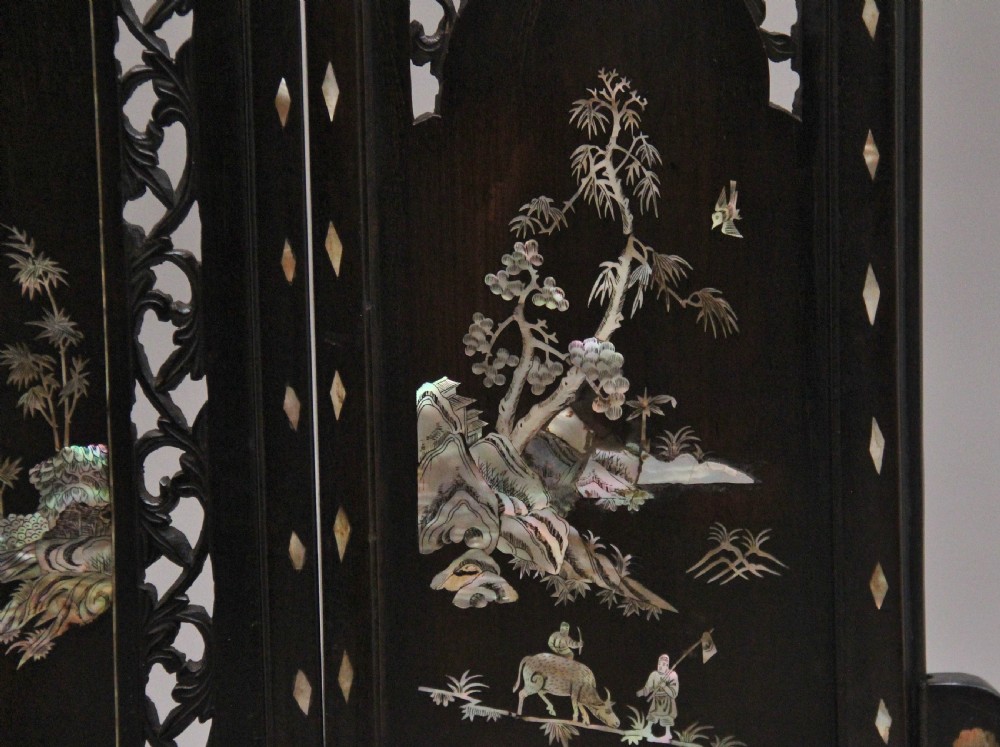 A 19th-century Chinese dark hardwood triptych table screen set with carved openwork borders and detailed mother-of-pearl landscape inlays. View XI