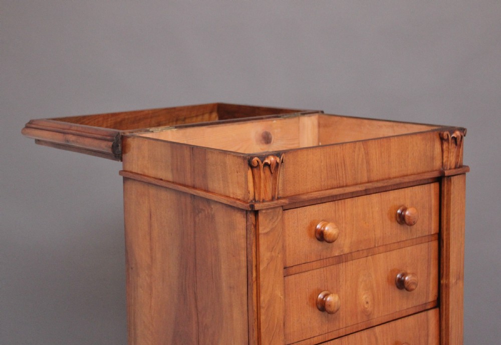 An early nineteenth-century Regency walnut Wellington chest featuring seven drawers with wooden knob handles and carved corbels at the top corners. View IX