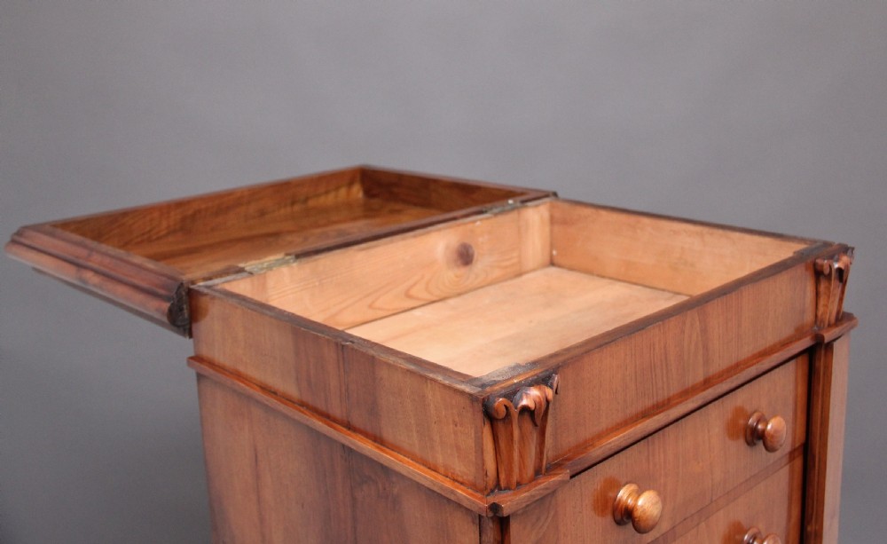 An early nineteenth-century Regency walnut Wellington chest featuring seven drawers with wooden knob handles and carved corbels at the top corners. View XI