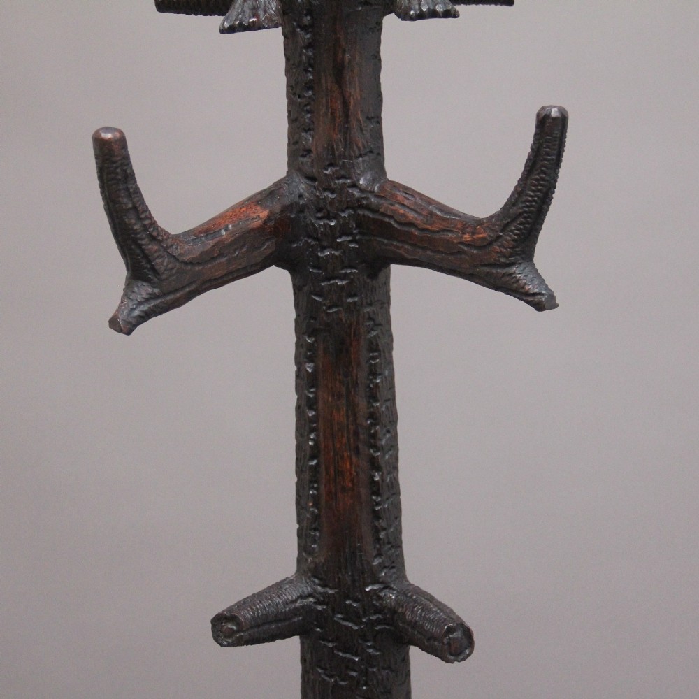 An early twentieth-century carved wooden Black Forest hall stand featuring a tree trunk stem with coat pegs, topped by a bear cub and supported at the base by a larger standing bear with an umbrella hoop and drip pan. View IX