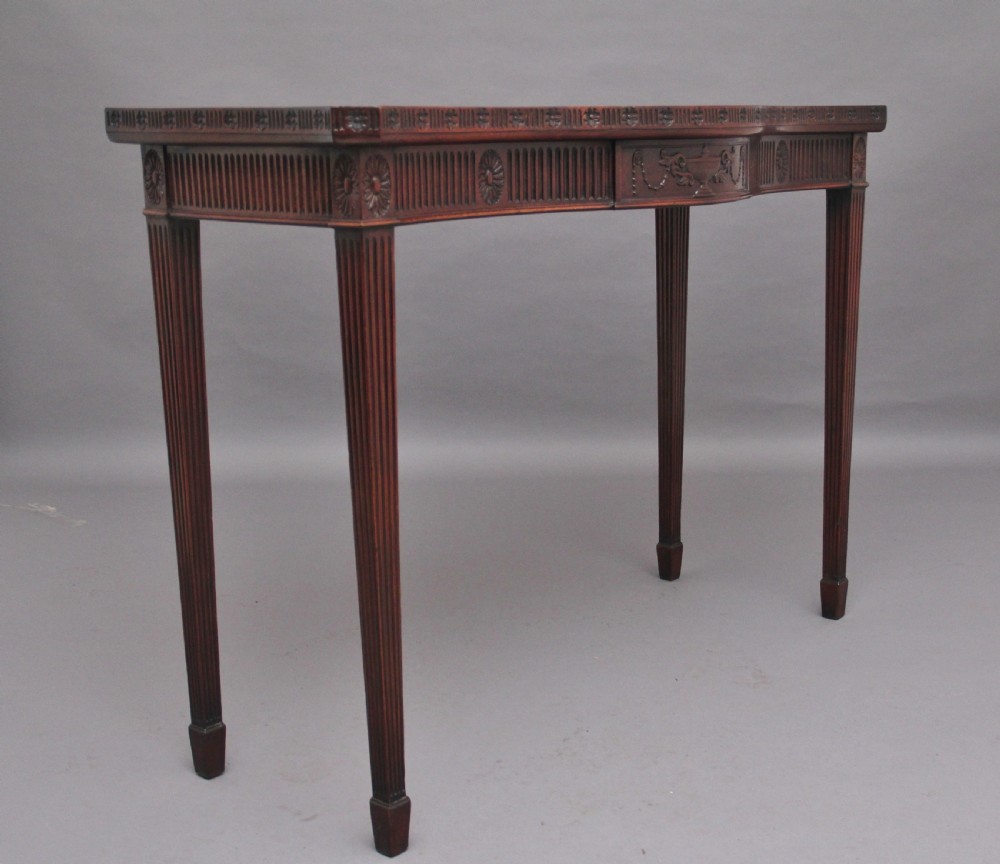 A dark mahogany serpentine console table with fluted legs and carved urn and garland motifs along the apron. View II