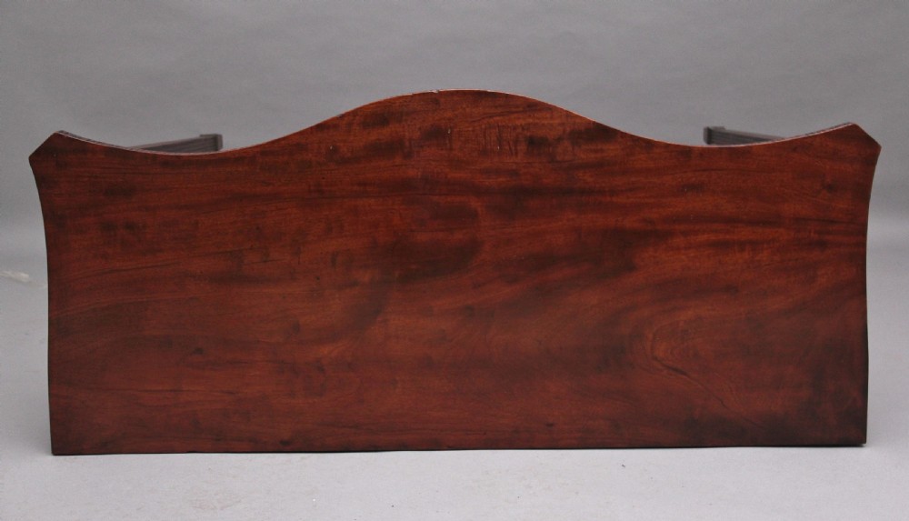 A dark mahogany serpentine console table with fluted legs and carved urn and garland motifs along the apron. View VI