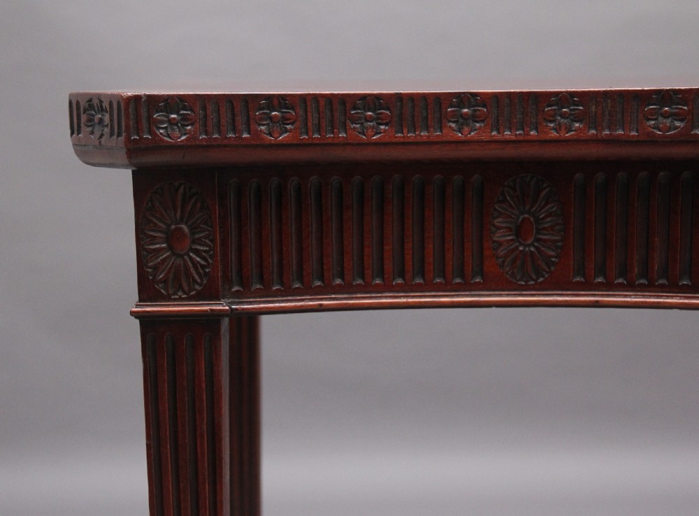 A dark mahogany serpentine console table with fluted legs and carved urn and garland motifs along the apron. View VIII