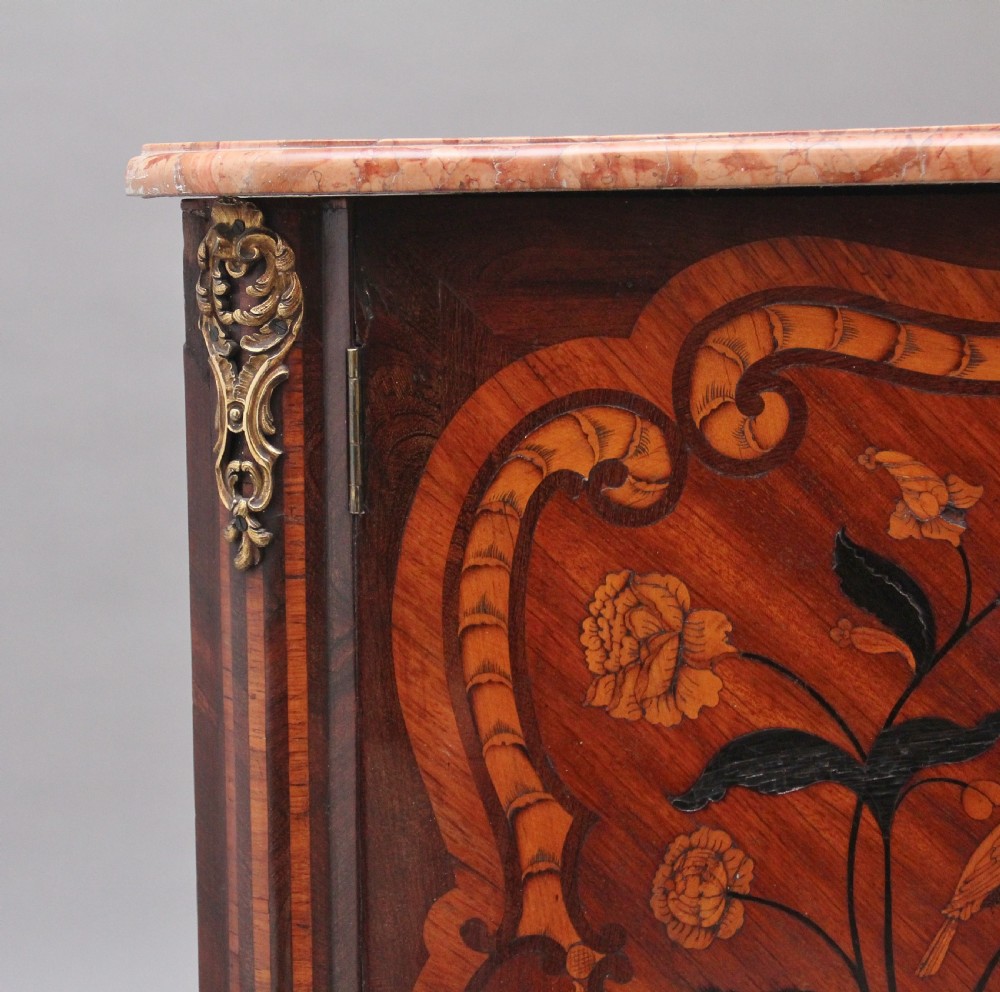 An 18th-century French corner cabinet featuring a curved front with intricate floral marquetry inlay, gilt bronze mounts, and a contoured marble top. View VIII