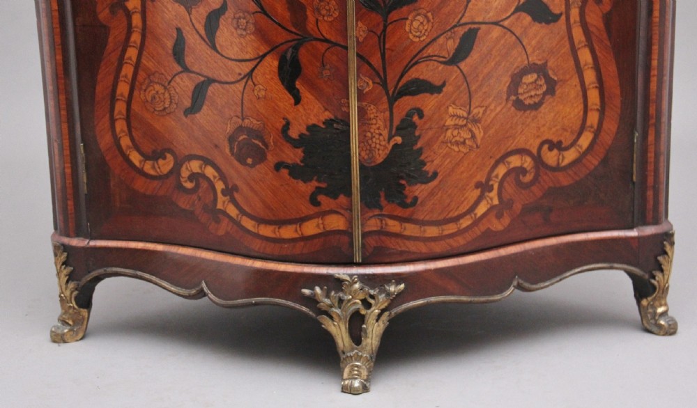 An 18th-century French corner cabinet featuring a curved front with intricate floral marquetry inlay, gilt bronze mounts, and a contoured marble top. View X