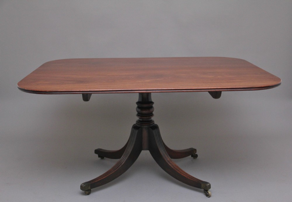 An early 19th-century mahogany tilt-top breakfast table with a rounded rectangular top shown in the upright position above a quadruped pedestal base with brass castors. View VIII