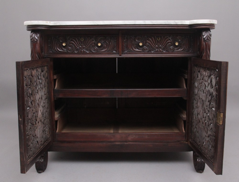 A 19th-century Anglo-Indian dark wood cabinet featuring a white marble top, two carved drawers, and two doors decorated with intricate pierced floral relief motifs. View III