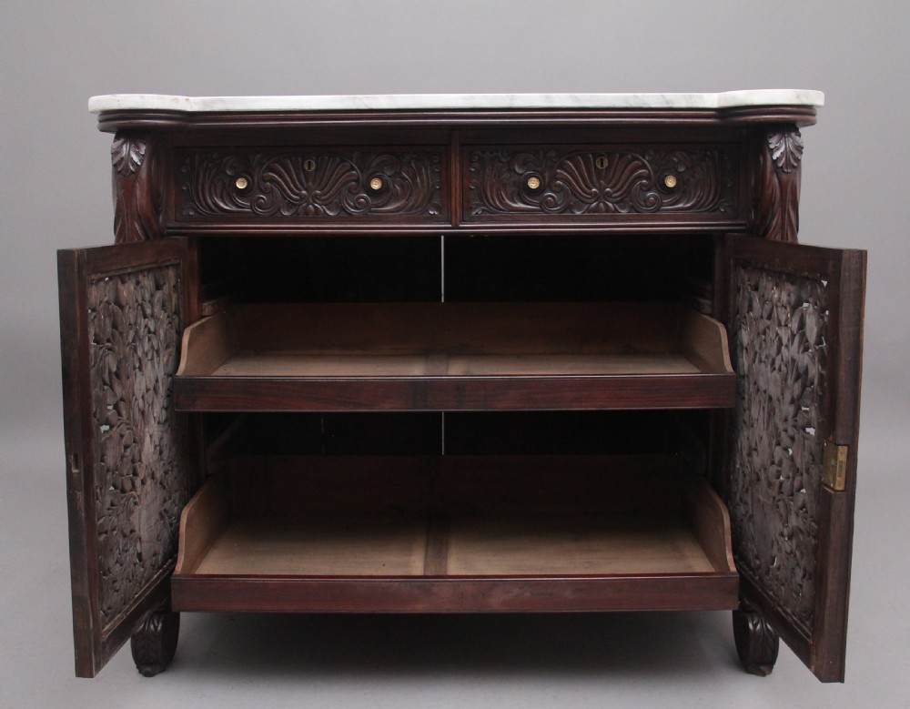 A 19th-century Anglo-Indian dark wood cabinet featuring a white marble top, two carved drawers, and two doors decorated with intricate pierced floral relief motifs. View V
