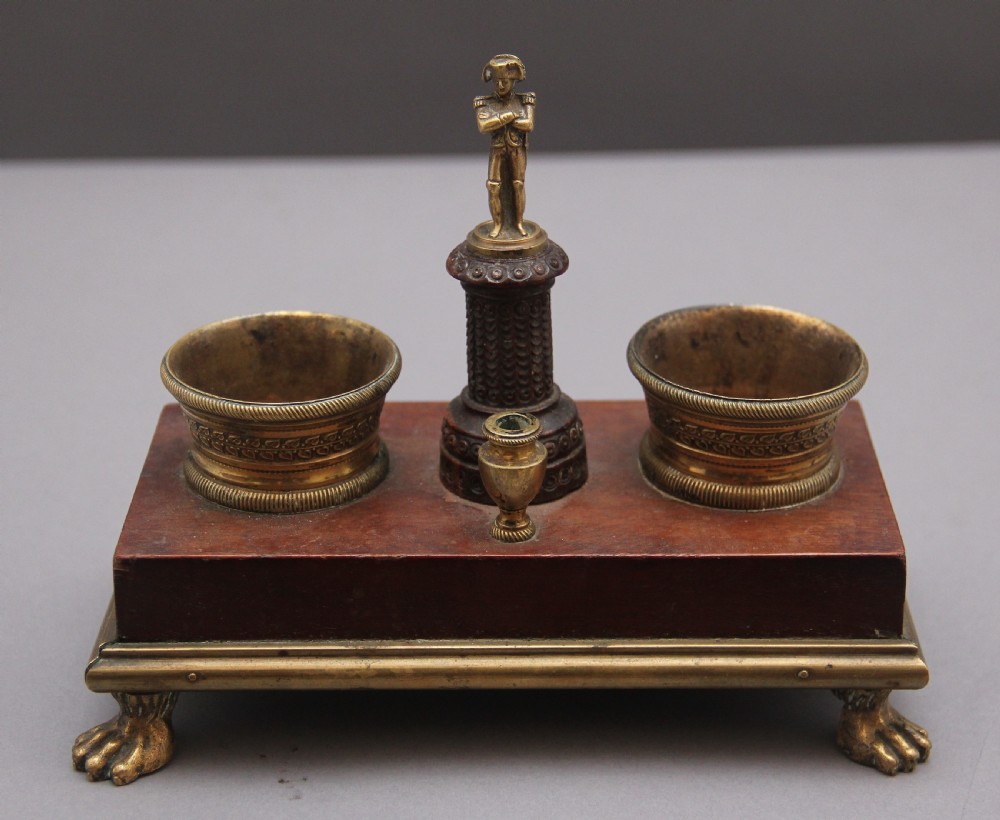 A 19th-century mahogany desk set featuring two metal inkwells, a central column topped with a small gilt figure, and four detailed claw feet. View III