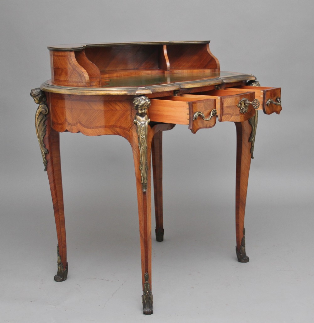 A 19th-century French kingwood writing table featuring ornate gilt-bronze mounts, cabriole legs, a green leather inset top, and a raised shelving superstructure. View II
