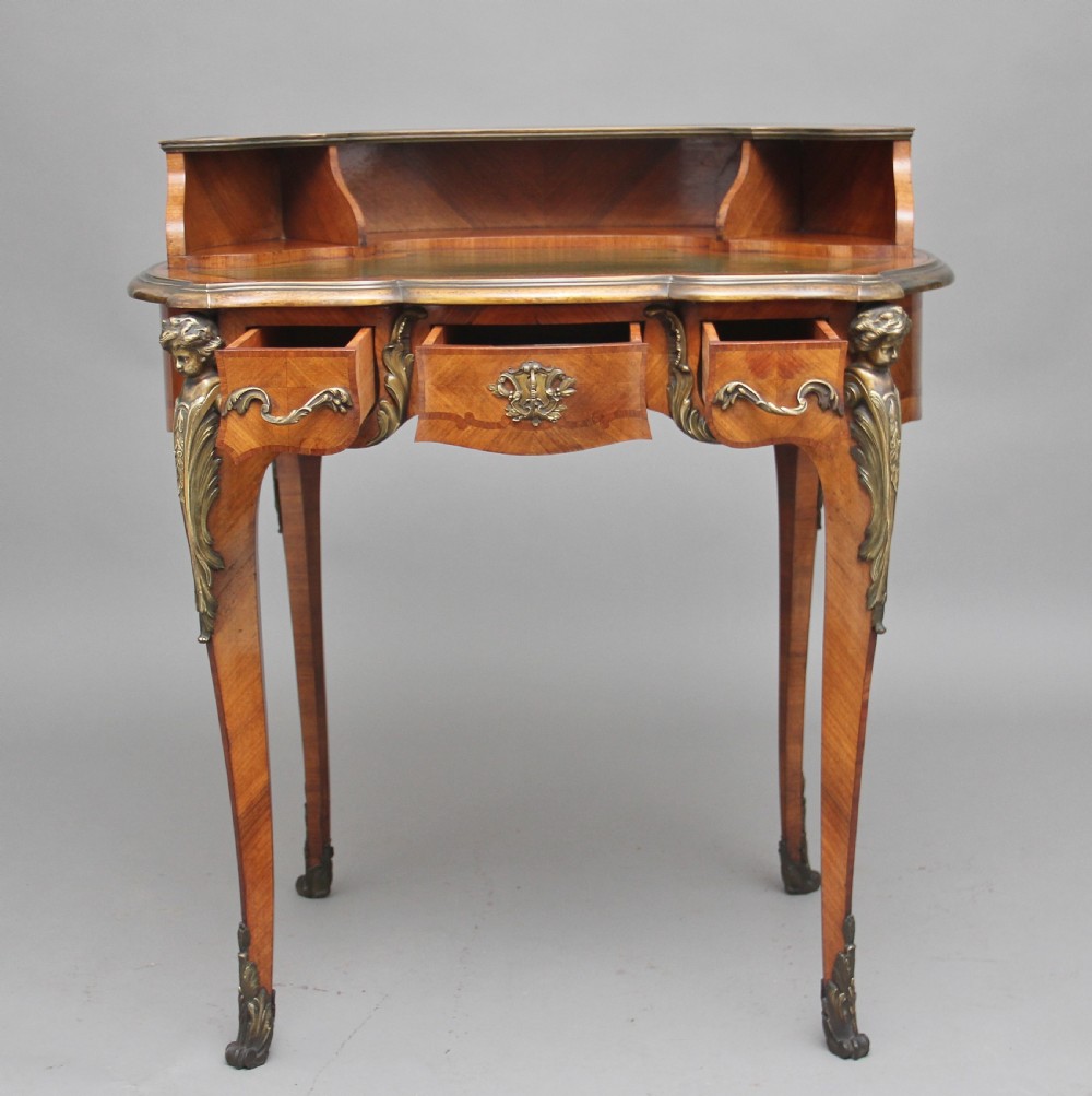 A 19th-century French kingwood writing table featuring ornate gilt-bronze mounts, cabriole legs, a green leather inset top, and a raised shelving superstructure. View III
