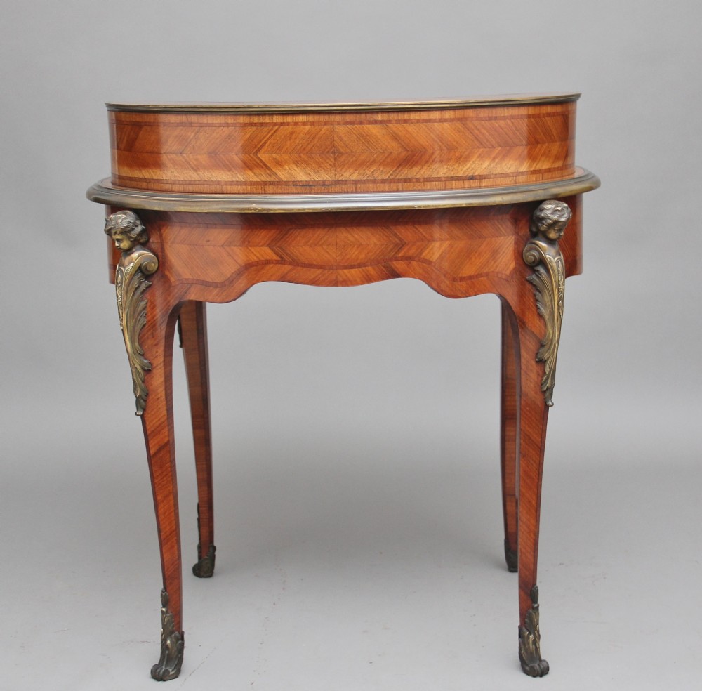 A 19th-century French kingwood writing table featuring ornate gilt-bronze mounts, cabriole legs, a green leather inset top, and a raised shelving superstructure. View VIII
