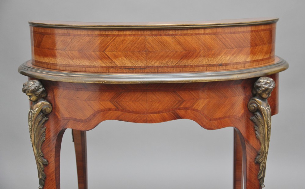 A 19th-century French kingwood writing table featuring ornate gilt-bronze mounts, cabriole legs, a green leather inset top, and a raised shelving superstructure. View XII