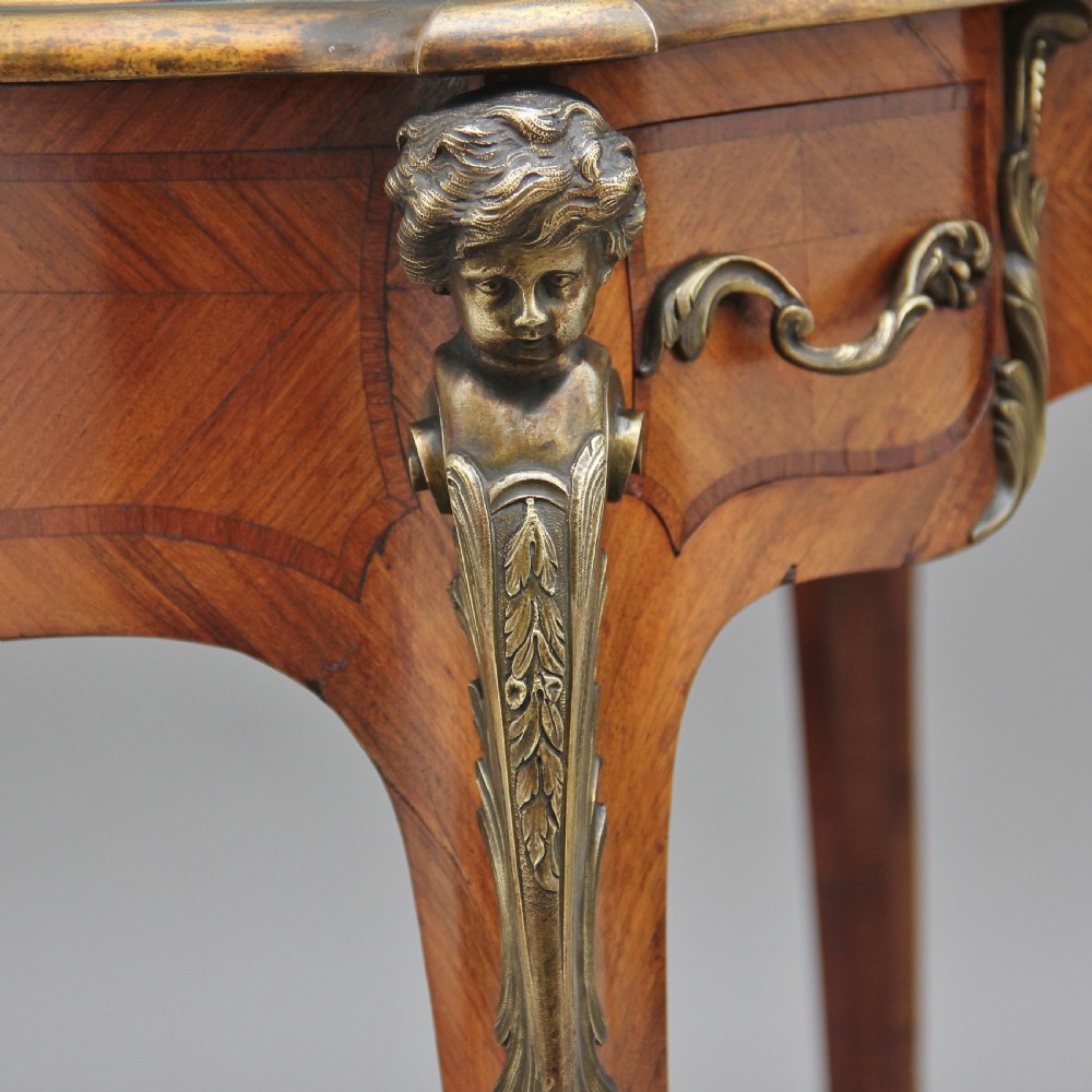 A 19th-century French kingwood writing table featuring ornate gilt-bronze mounts, cabriole legs, a green leather inset top, and a raised shelving superstructure. View XVI