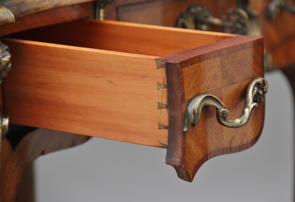 A 19th-century French kingwood writing table featuring ornate gilt-bronze mounts, cabriole legs, a green leather inset top, and a raised shelving superstructure. View XVII
