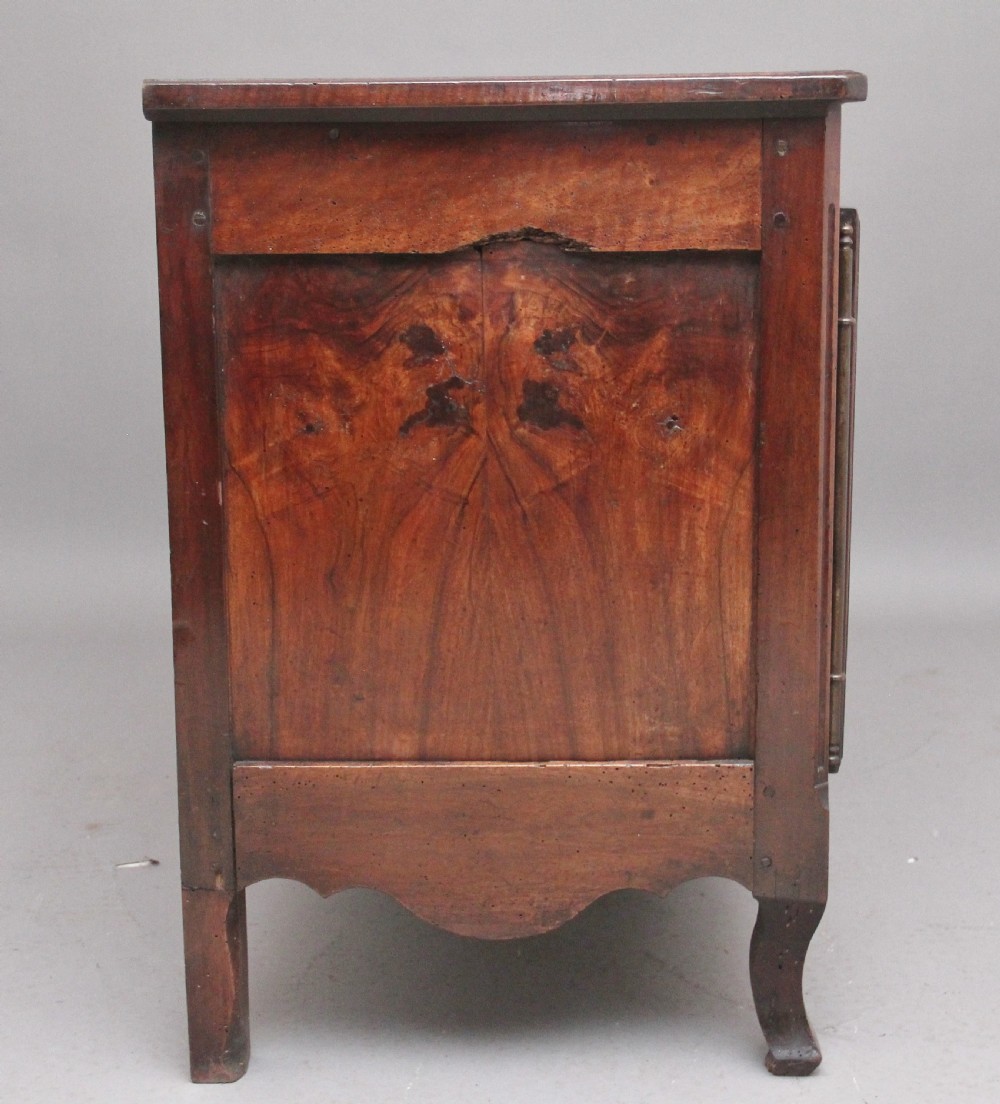 An early nineteenth-century French cherrywood dresser base featuring two cupboard doors with shaped panels, central fluting, decorative brass escutcheons, and short cabriole legs. View III