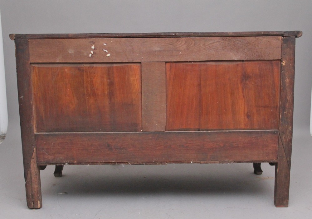 An early nineteenth-century French cherrywood dresser base featuring two cupboard doors with shaped panels, central fluting, decorative brass escutcheons, and short cabriole legs. View V