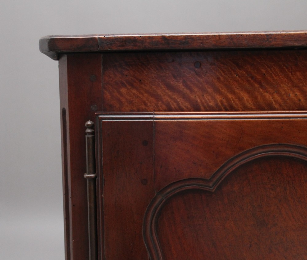 An early nineteenth-century French cherrywood dresser base featuring two cupboard doors with shaped panels, central fluting, decorative brass escutcheons, and short cabriole legs. View VIII