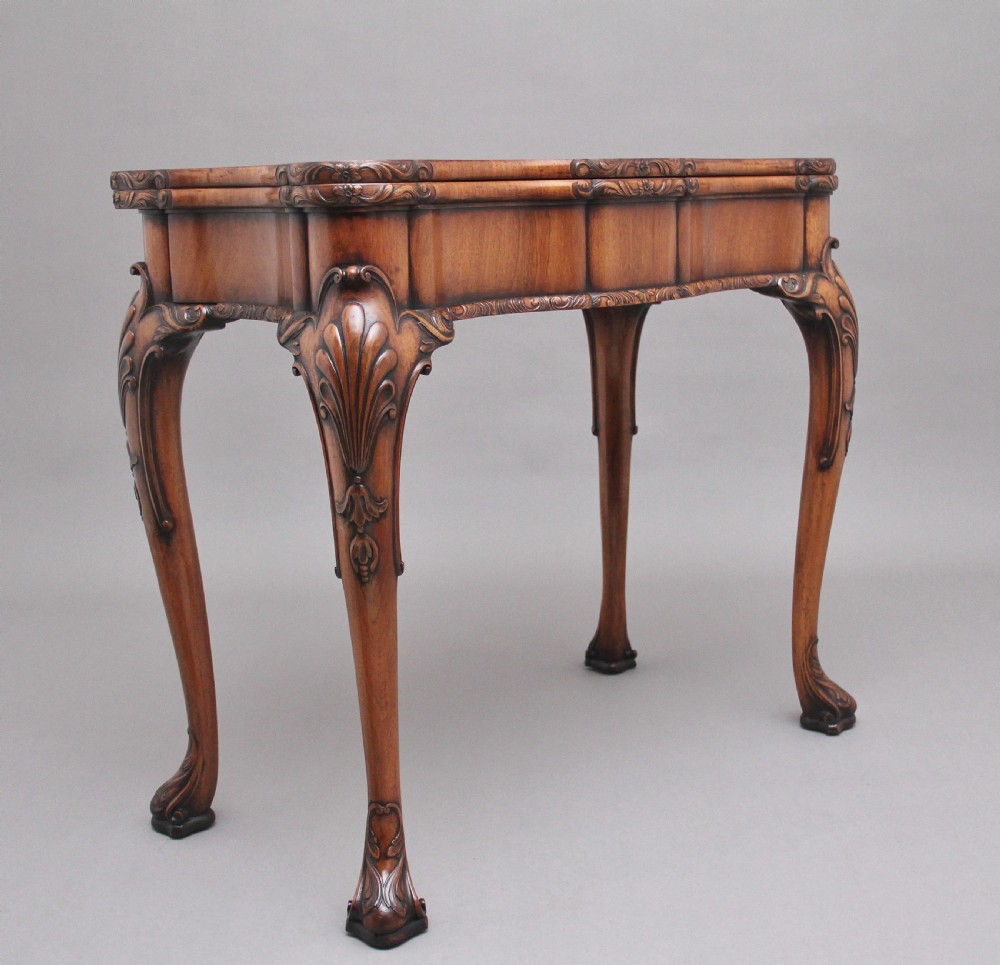 An early twentieth-century carved walnut card table featuring cabriole legs with shell motifs and a contoured apron.