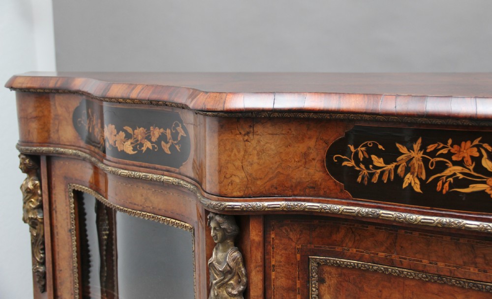 A 19th-century burr walnut credenza featuring a central door with floral marquetry inlay, flanked by two curved glazed doors and detailed ormolu mounts. View XII
