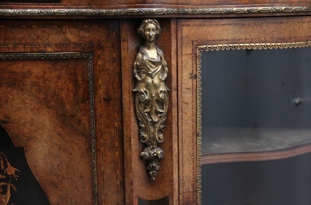 A 19th-century burr walnut credenza featuring a central door with floral marquetry inlay, flanked by two curved glazed doors and detailed ormolu mounts. View XVI