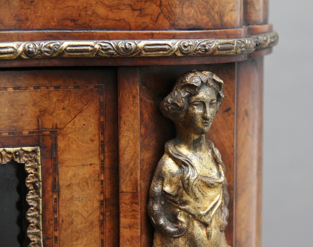 A 19th-century burr walnut credenza featuring a central door with floral marquetry inlay, flanked by two curved glazed doors and detailed ormolu mounts. View XVIII