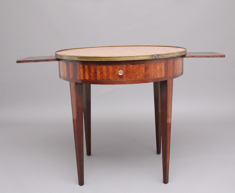 A 19th-century French oval centre table featuring kingwood parquetry, tapered square legs, a single drawer, and a brass gallery top rim. View II