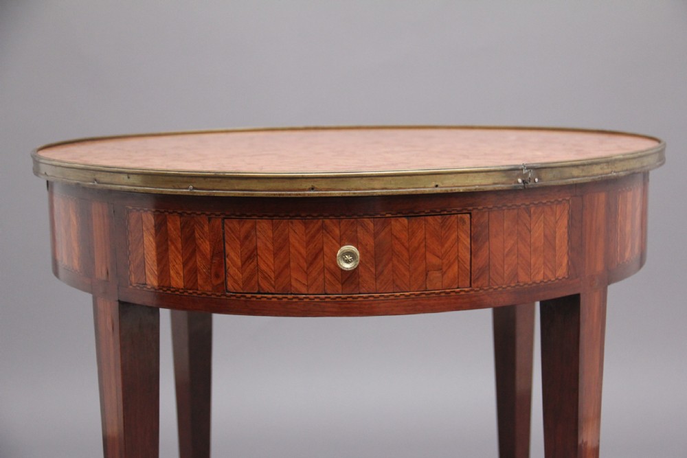 A 19th-century French oval centre table featuring kingwood parquetry, tapered square legs, a single drawer, and a brass gallery top rim. View VI