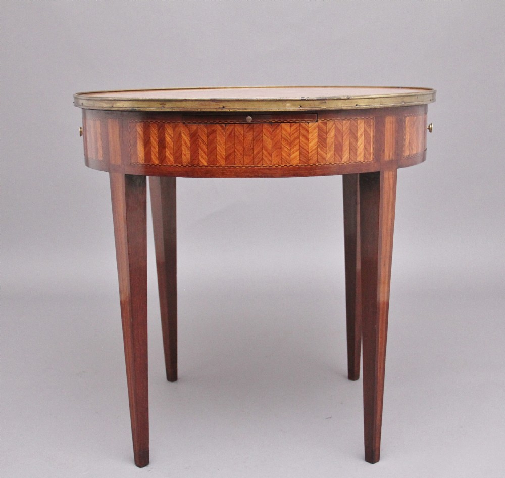 A 19th-century French oval centre table featuring kingwood parquetry, tapered square legs, a single drawer, and a brass gallery top rim. View VII