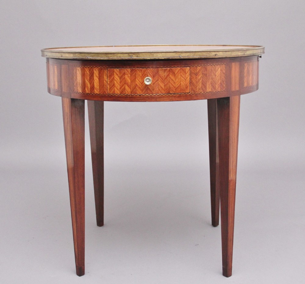 A 19th-century French oval centre table featuring kingwood parquetry, tapered square legs, a single drawer, and a brass gallery top rim. View VIII