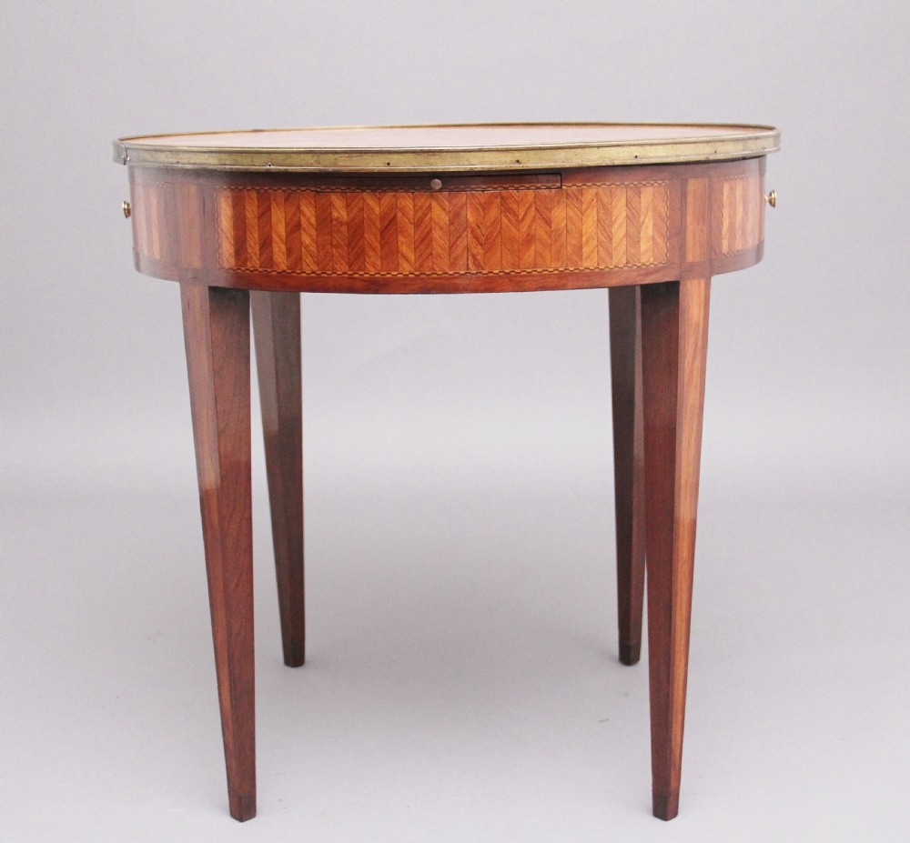 A 19th-century French oval centre table featuring kingwood parquetry, tapered square legs, a single drawer, and a brass gallery top rim. View IX