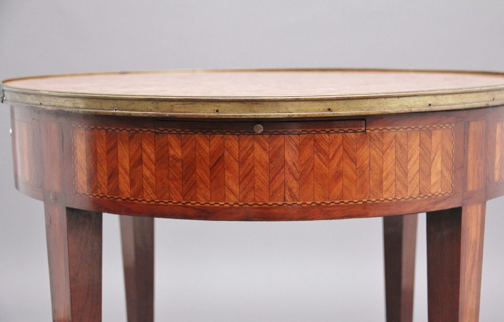 A 19th-century French oval centre table featuring kingwood parquetry, tapered square legs, a single drawer, and a brass gallery top rim. View X
