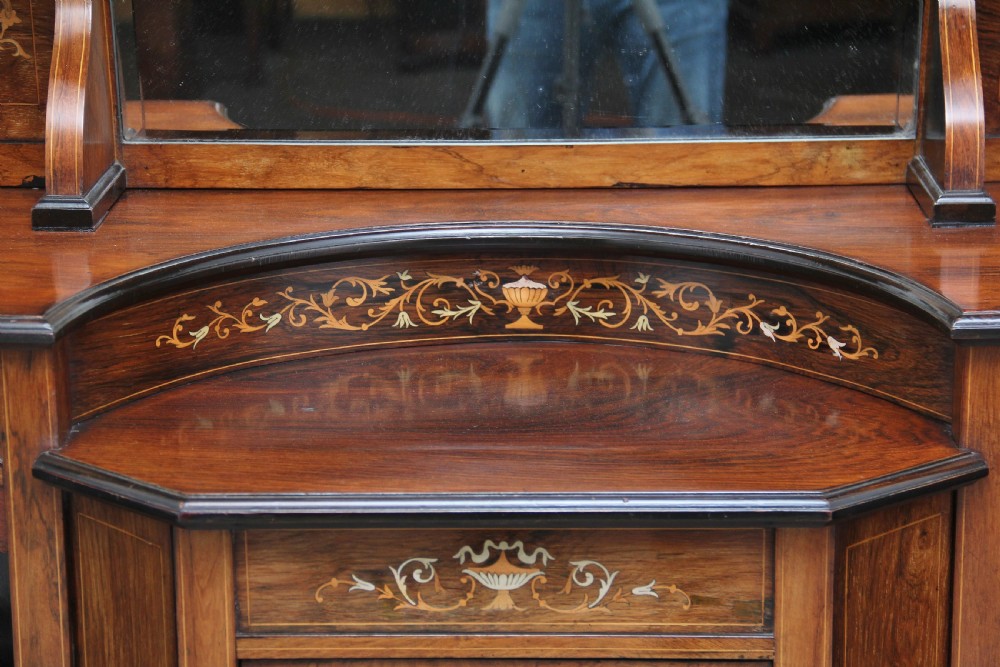 A 19th-century rosewood display cabinet featuring intricate marquetry urn inlays, mirror backs, lattice glazed doors, and a broken pediment top. View VI