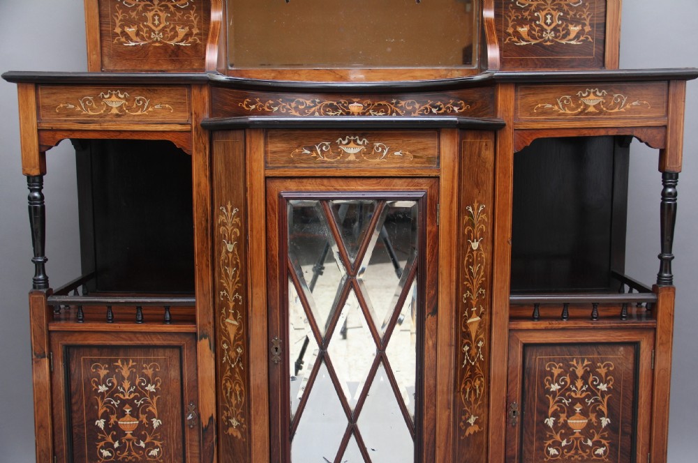 A 19th-century rosewood display cabinet featuring intricate marquetry urn inlays, mirror backs, lattice glazed doors, and a broken pediment top. View VIII
