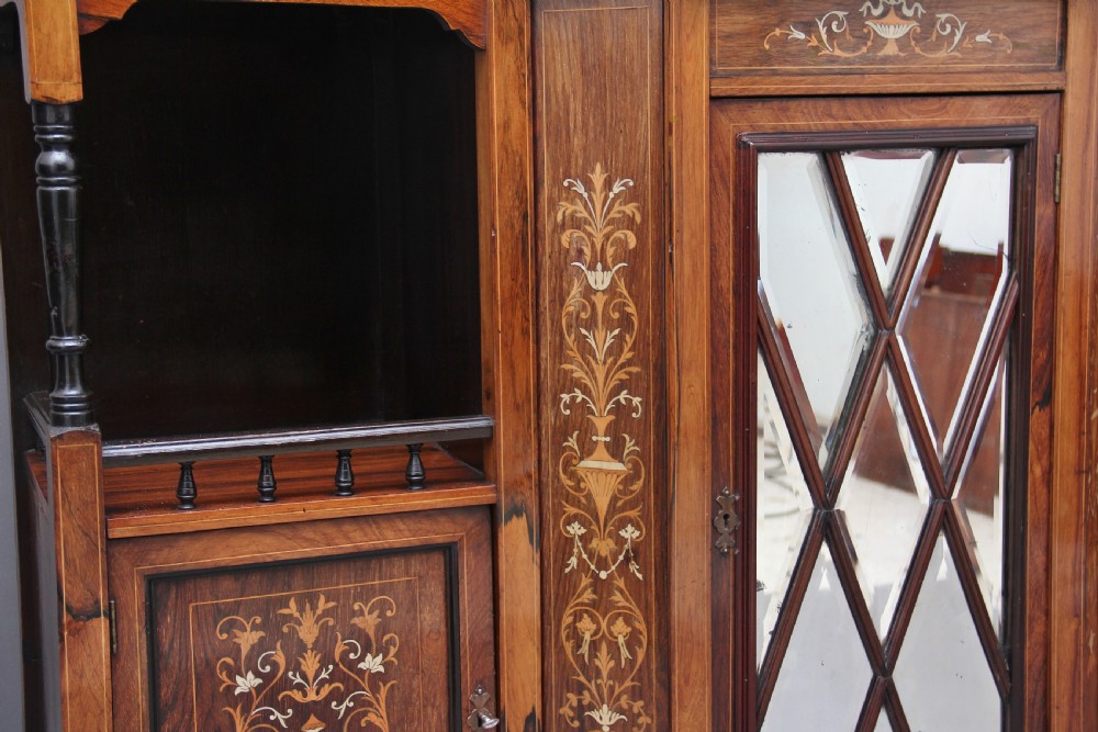 A 19th-century rosewood display cabinet featuring intricate marquetry urn inlays, mirror backs, lattice glazed doors, and a broken pediment top. View XV