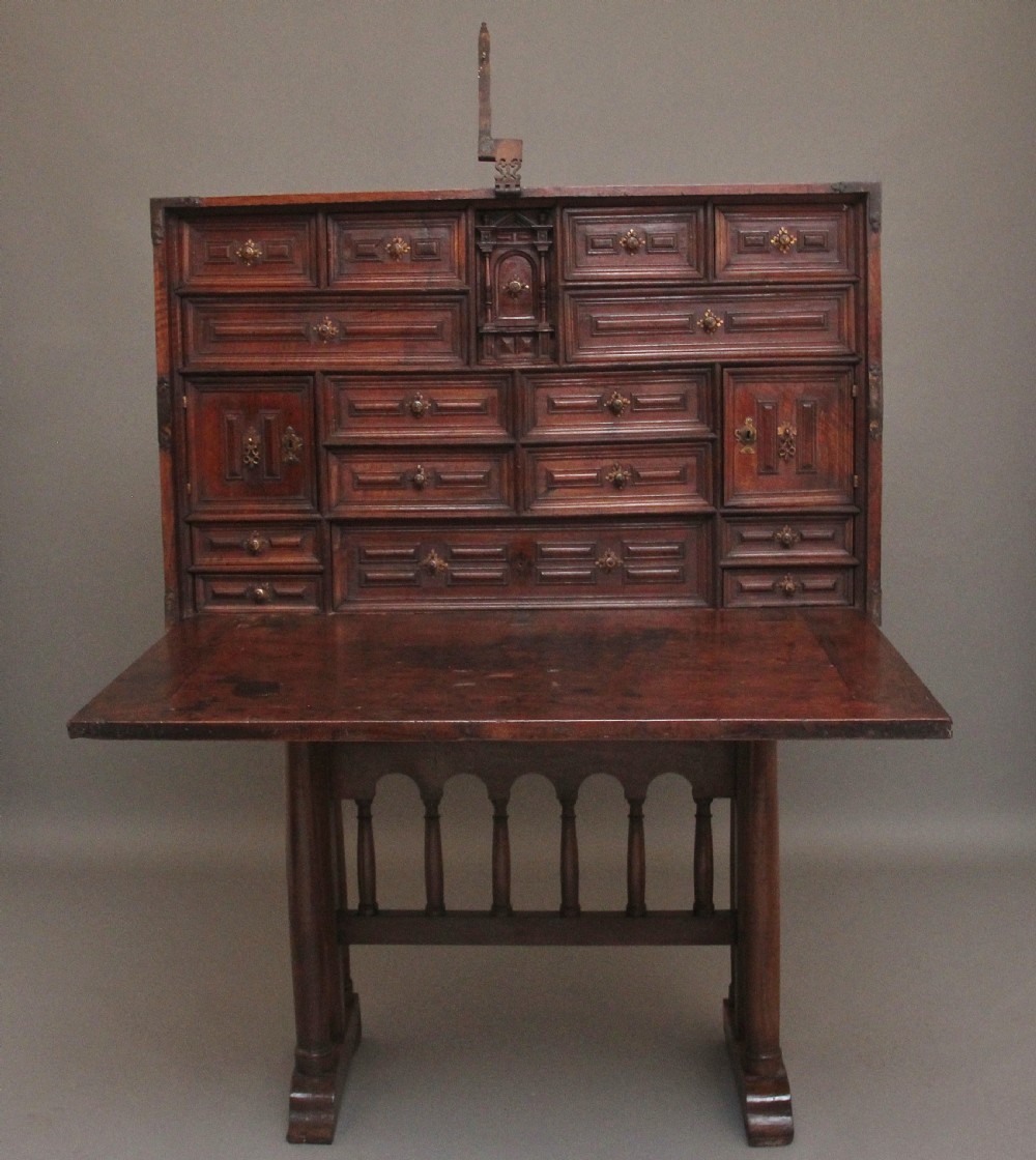 A seventeenth-century Spanish walnut vargueno writing cabinet featuring intricate wrought iron lockplates and handles resting on a turned trestle stand. View II