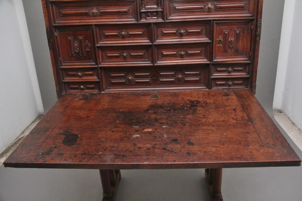 A seventeenth-century Spanish walnut vargueno writing cabinet featuring intricate wrought iron lockplates and handles resting on a turned trestle stand. View III