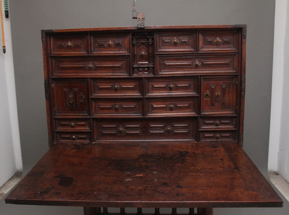 A seventeenth-century Spanish walnut vargueno writing cabinet featuring intricate wrought iron lockplates and handles resting on a turned trestle stand. View V
