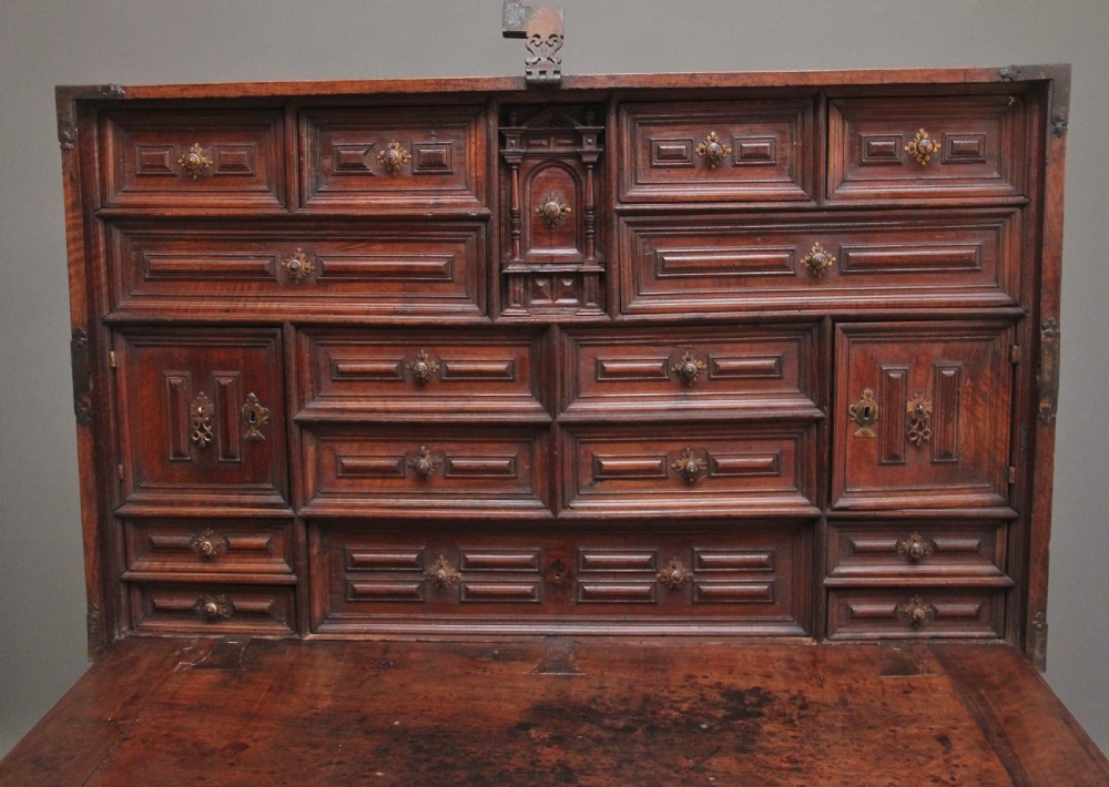 A seventeenth-century Spanish walnut vargueno writing cabinet featuring intricate wrought iron lockplates and handles resting on a turned trestle stand. View VI