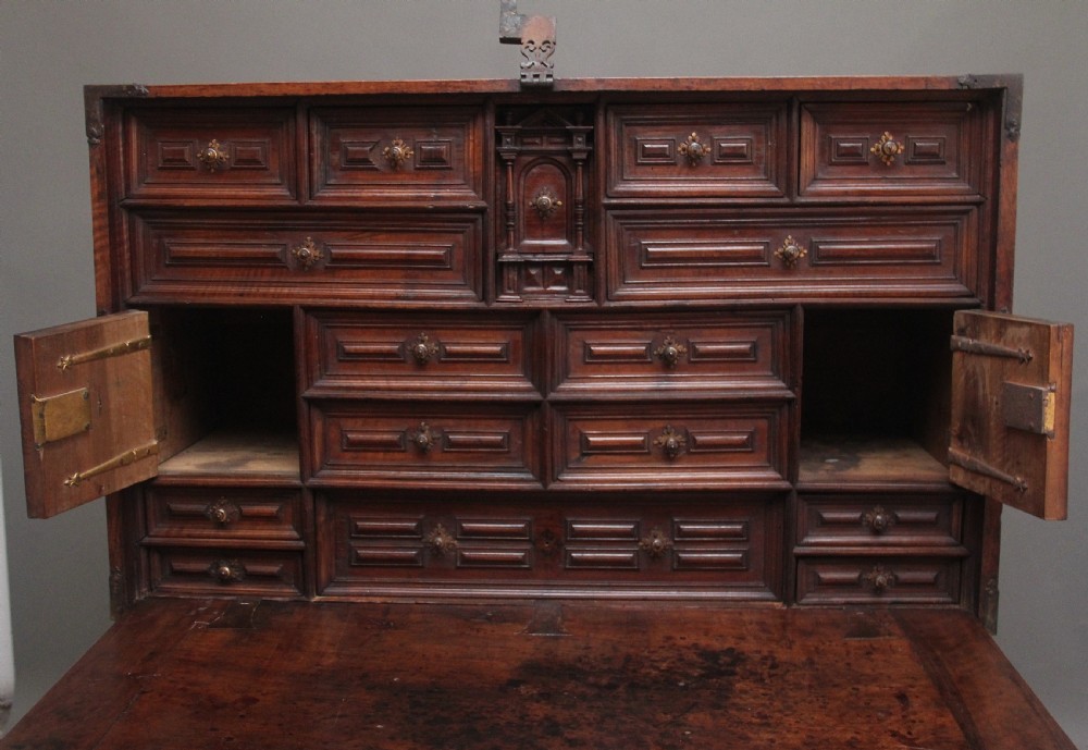 A seventeenth-century Spanish walnut vargueno writing cabinet featuring intricate wrought iron lockplates and handles resting on a turned trestle stand. View VII