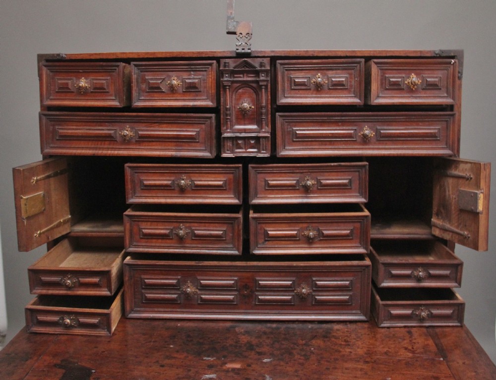 A seventeenth-century Spanish walnut vargueno writing cabinet featuring intricate wrought iron lockplates and handles resting on a turned trestle stand. View IX