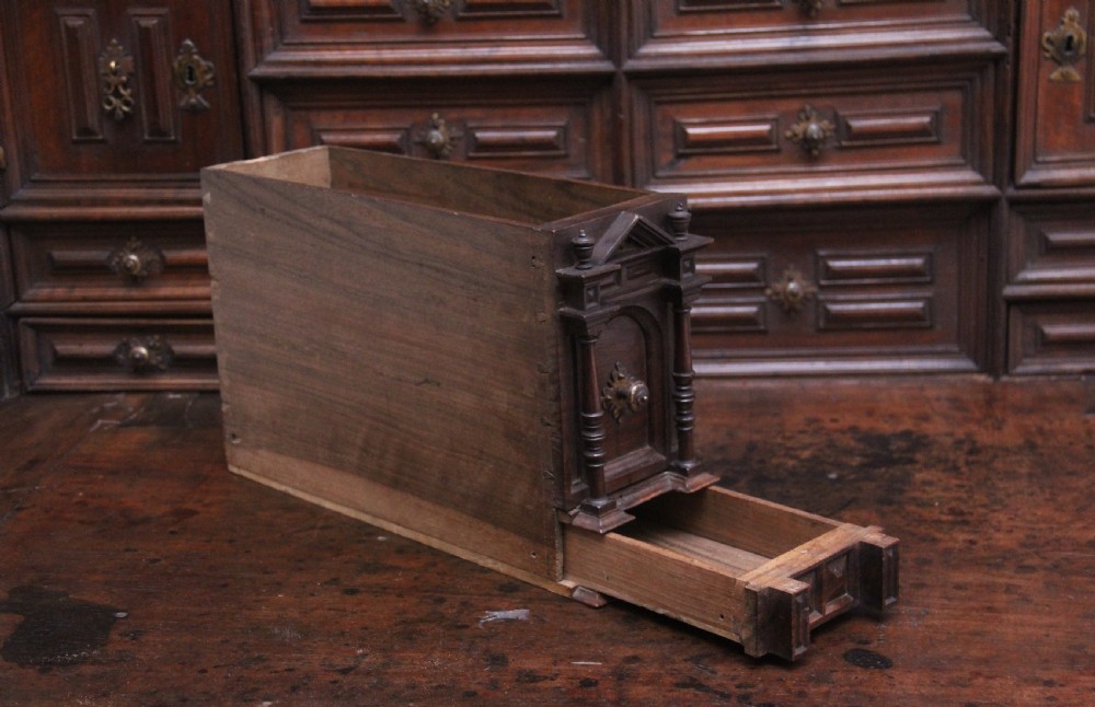 A seventeenth-century Spanish walnut vargueno writing cabinet featuring intricate wrought iron lockplates and handles resting on a turned trestle stand. View X