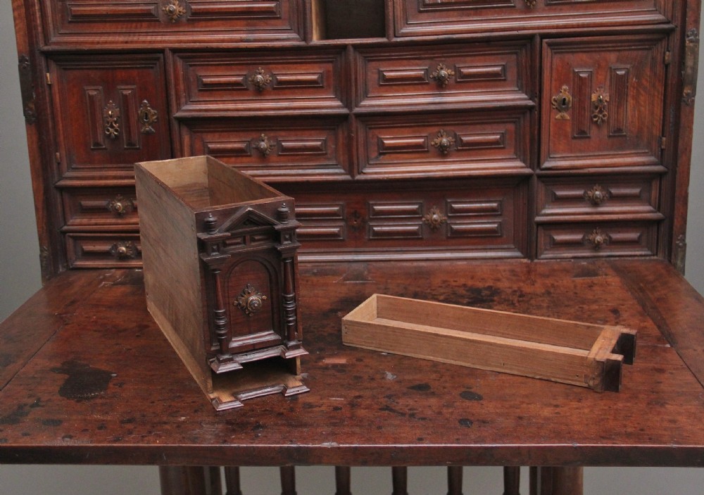 A seventeenth-century Spanish walnut vargueno writing cabinet featuring intricate wrought iron lockplates and handles resting on a turned trestle stand. View XI