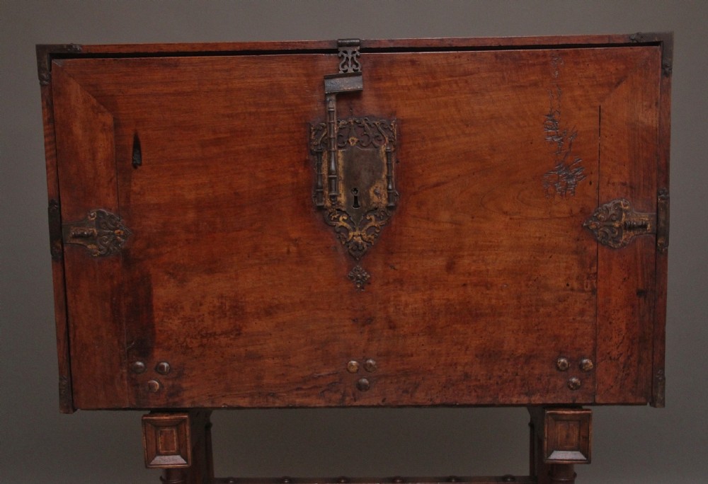 A seventeenth-century Spanish walnut vargueno writing cabinet featuring intricate wrought iron lockplates and handles resting on a turned trestle stand. View XII