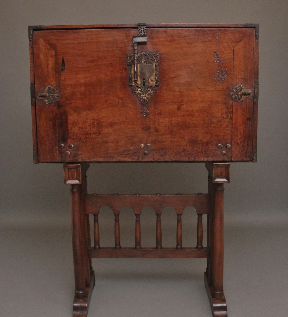 A seventeenth-century Spanish walnut vargueno writing cabinet featuring intricate wrought iron lockplates and handles resting on a turned trestle stand. View XIX