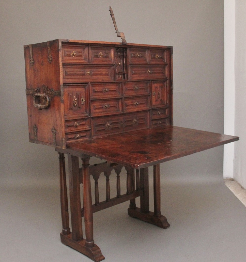 A seventeenth-century Spanish walnut vargueno writing cabinet featuring intricate wrought iron lockplates and handles resting on a turned trestle stand. View XX