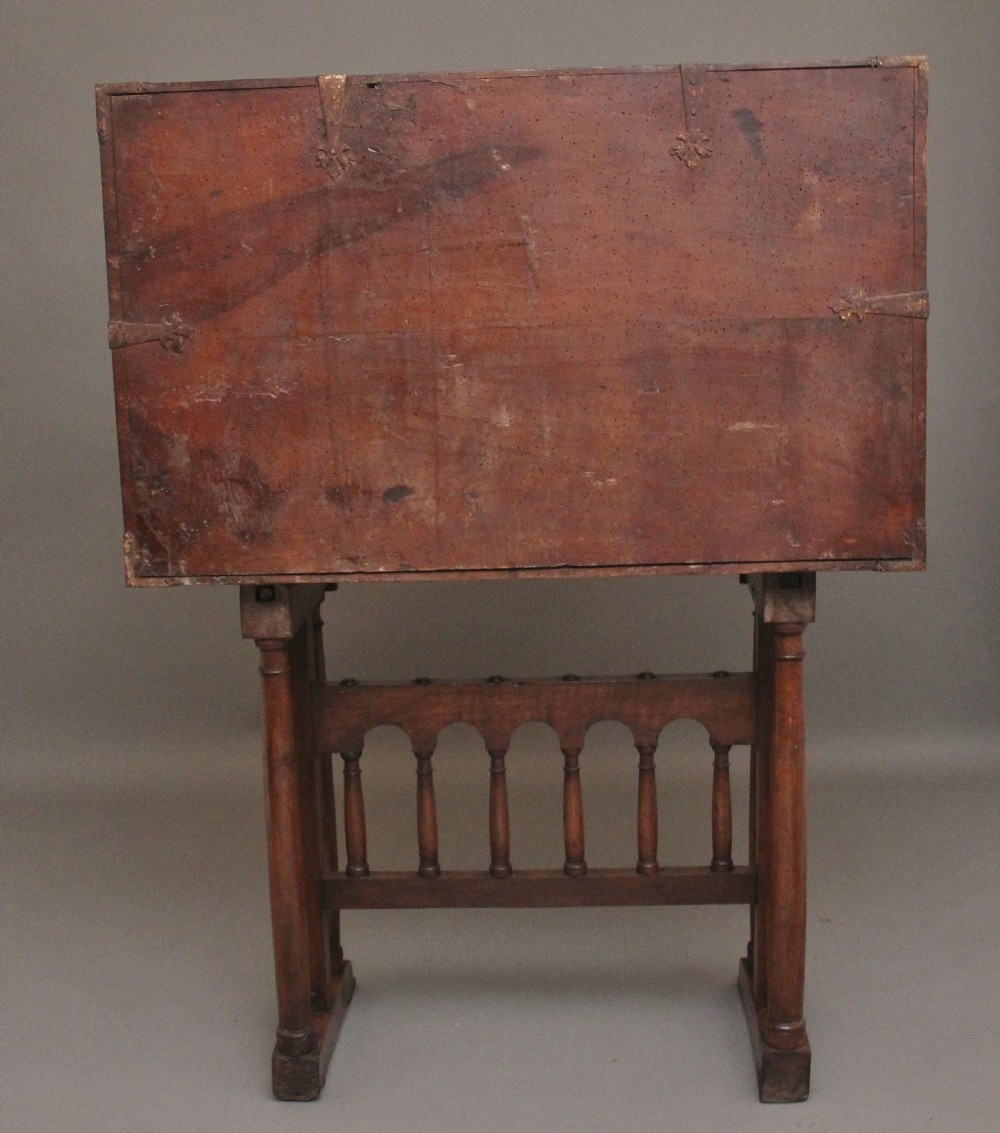 A seventeenth-century Spanish walnut vargueno writing cabinet featuring intricate wrought iron lockplates and handles resting on a turned trestle stand. View XXV