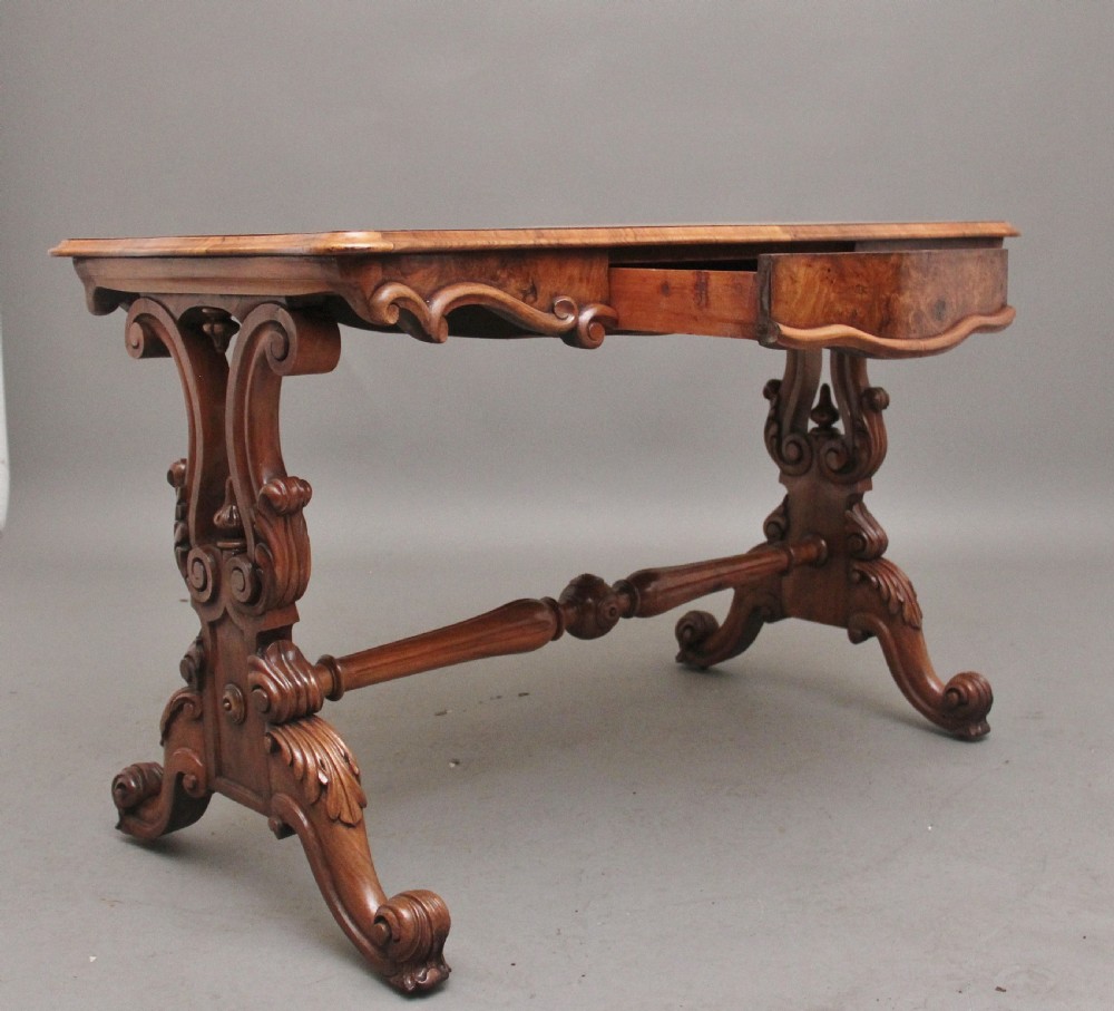 A 19th-century burr walnut centre table featuring a serpentine top and elaborate carved scroll supports joined by a turned stretcher. View II